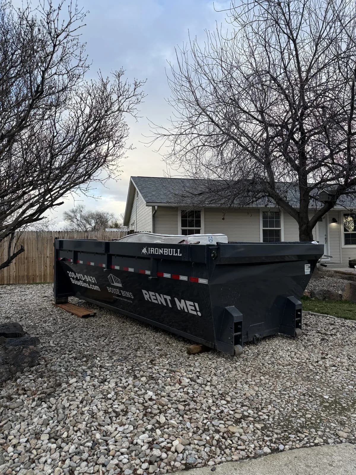 Boards under a 15 yard roll-off dumpster on a gravel driveway in Boise, ID - Boise Bins